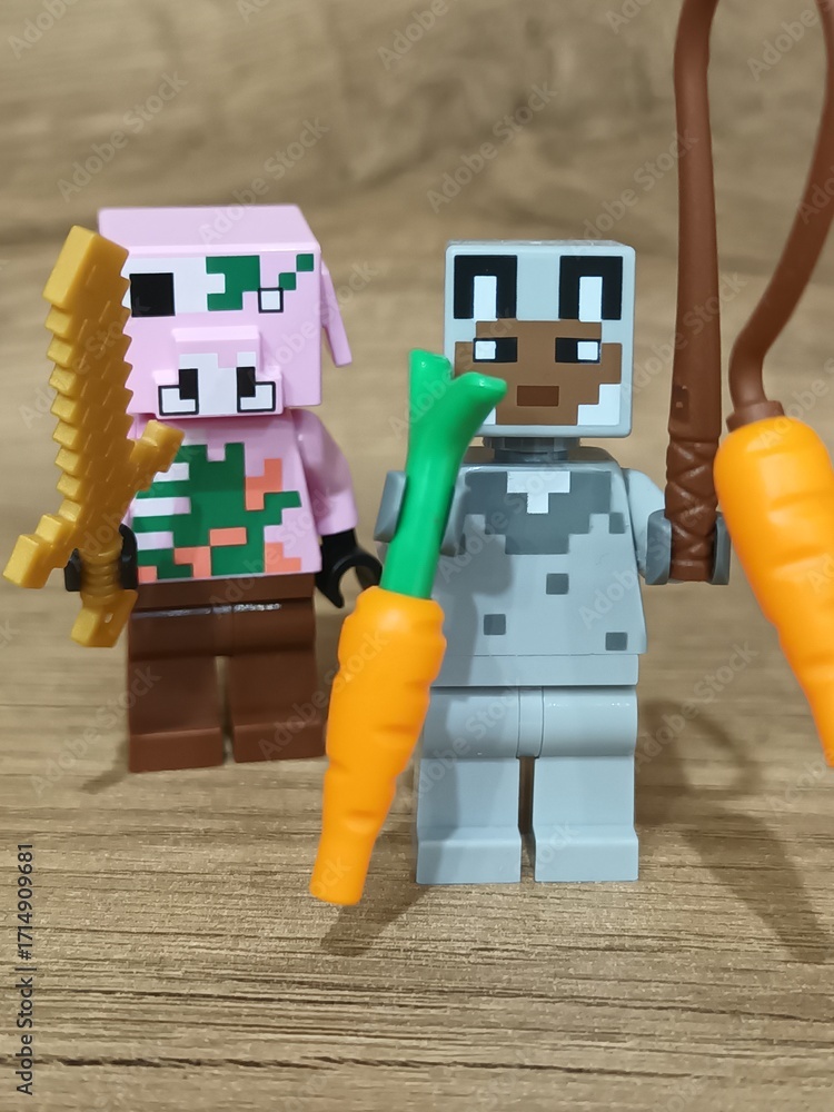 Naklejka premium Whimsical block figures a pink pig-like character with a golden weapon and a grey animal holding a fresh carrot, posed on wood, symbolizing fantasy play and imaginative adventure