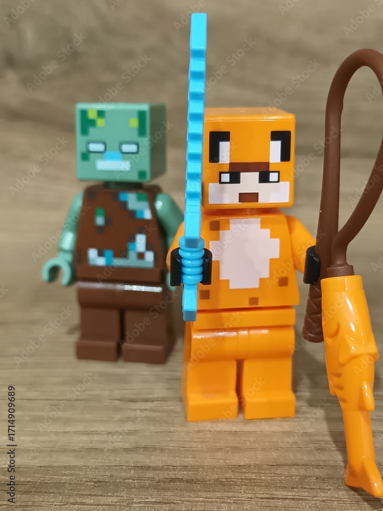 Obraz premium Whimsical block figures a pink pig-like character with a golden weapon and a grey animal holding a fresh carrot, posed on wood, symbolizing fantasy play and imaginative adventure