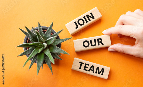 Join our team symbol. Wooden blocks with words Join our team. Beautiful orange background with succulent plant. Businessman hand. Business and Join our team concept. Copy space.