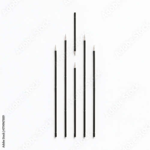 Black pen refills arranged in straight road on white background