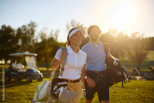 Happy couple of golfers enjoying in playing golf at sunset.