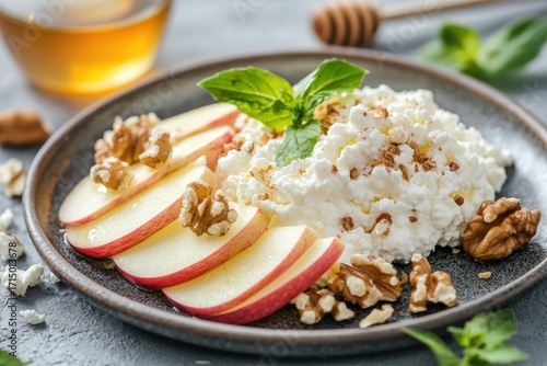 Healthy snack of cottage cheese, apple slices, and walnuts on a dark plate with honey in the background