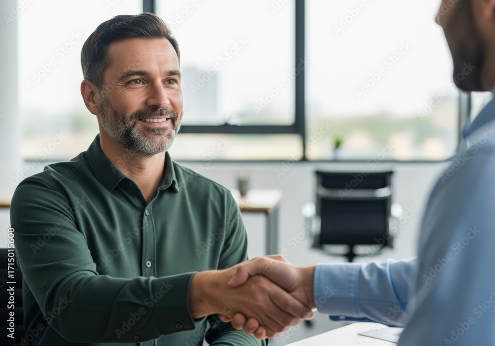 Fototapeta premium Two businessmen shaking hands in a modern office environment celebrating a successful partnership and agreement