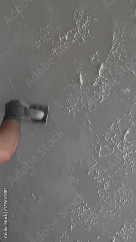 master painter builder creates a pattern on decorative plaster with a spatula and trowel