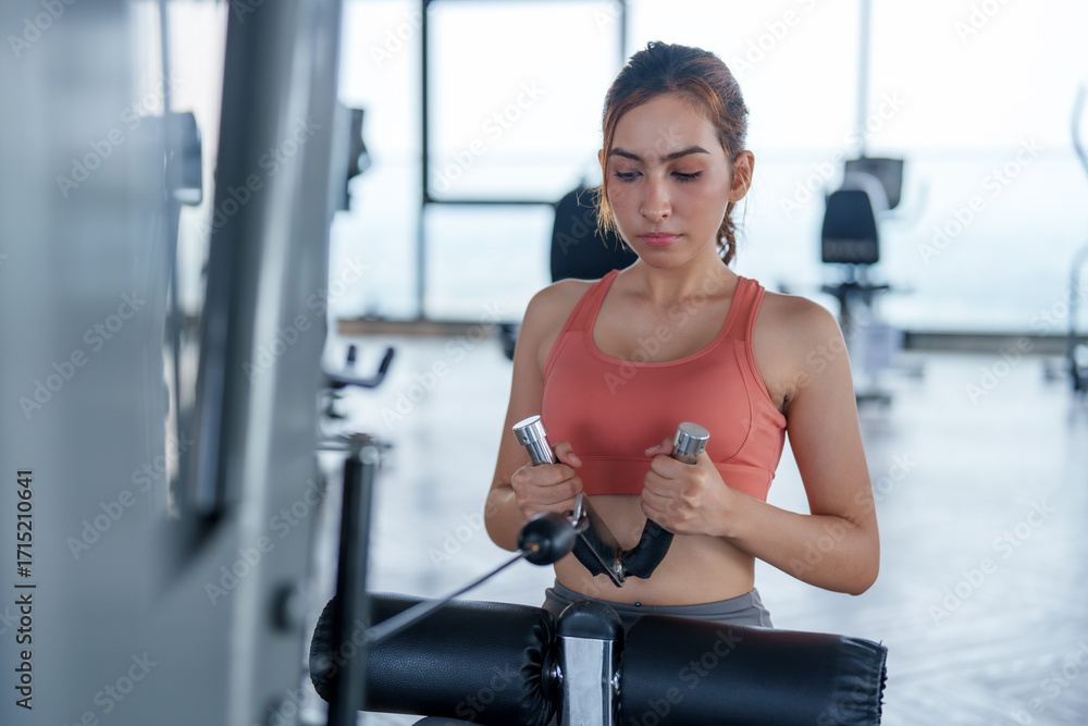 Fototapeta premium Young woman engages in focused workout at gym, demonstrating dedication to fitness and self care. Her exercise routine promotes wellness and healthy lifestyle
