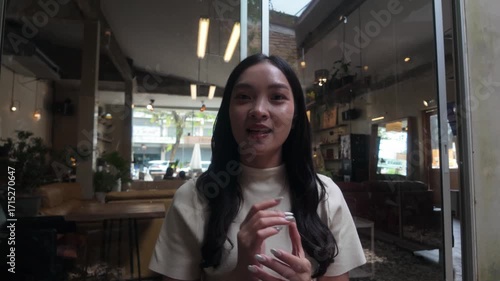 Confident and stunning young Asian businesswoman energetically engaging with the camera while recording a vlog or delivering a presentation