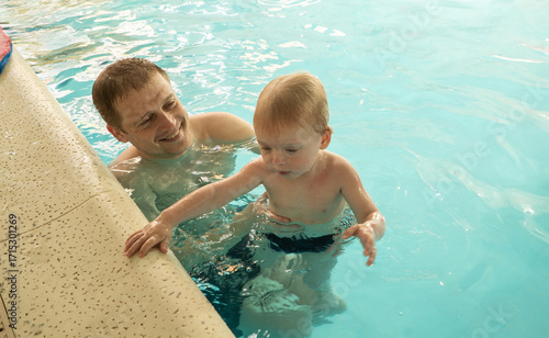 A man is holding a baby in a pool