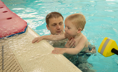 A man is holding a child in a pool