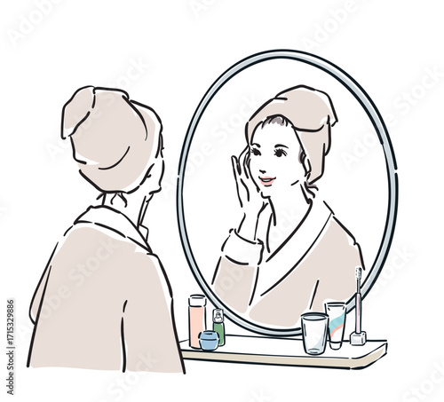 鏡の前に立つバスローブ姿の女性