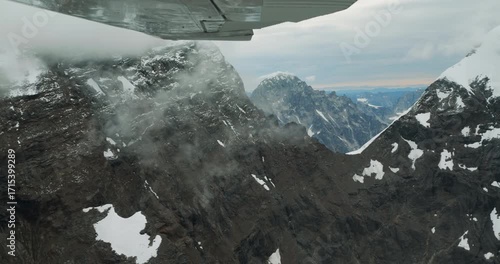 Aerial shot of snowy peaks in Alaska. Flying small plane along Denali National Park high mountains	