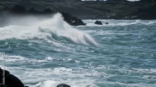Powerful waves crash against dark volcanic rocks, creating a dramatic coastal scene.