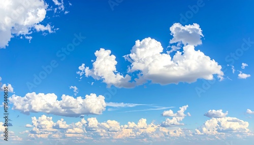 A vast expanse of brilliant blue sky, dotted with fluffy, white cumulus clouds, creates a serene and peaceful scene.