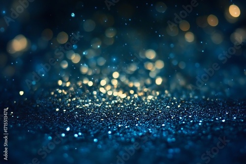 Abstract blue background with sparkling golden bokeh lights and glitter particles