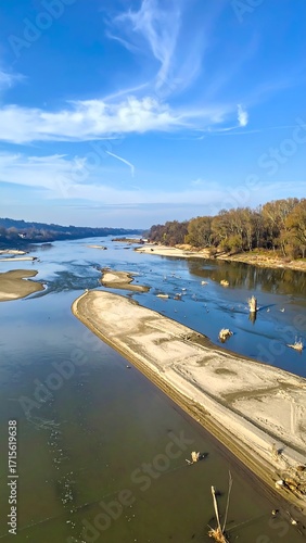High-angle view of a riverbed with exposed sandbars under a vibrant blue sky.