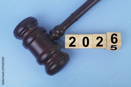 Wooden judge gavel and flipping numbers 2025 and 2026 on cubes. Changing in legal system concept.