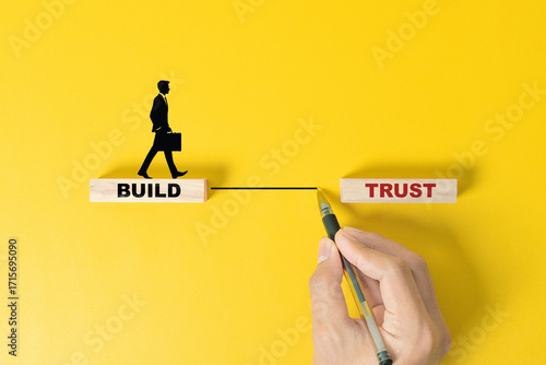 Build trust symbol. Concept words Build trust on wooden blocks on a beautiful yellow table yellow background. Businessman hand. Business and build trust concept, copy space