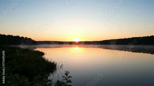 Serene sunrise over a misty lake, casting warm golden light across the tranquil water.