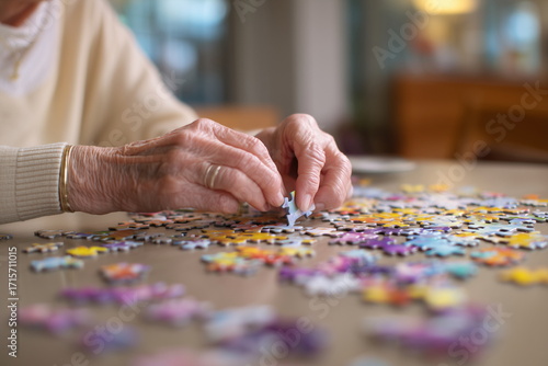 A female elder focused on solving a colorful jigsaw puzzle at a rehabilitation center, hands gently placing pieces, calm and therapeutic atmosphere promoting cognitive activity.
