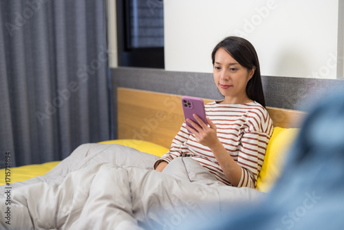 Woman sitting in bed using mobile phone device