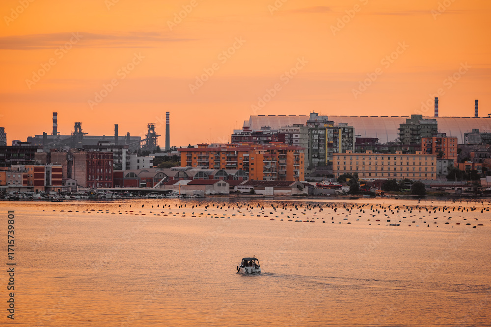 Naklejka premium Orange sky and Taranto skyline reflection