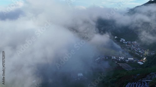 Drone Orbit Shot of Mountain Village and Farmlands Covered in Dense Fog in the Highlands
