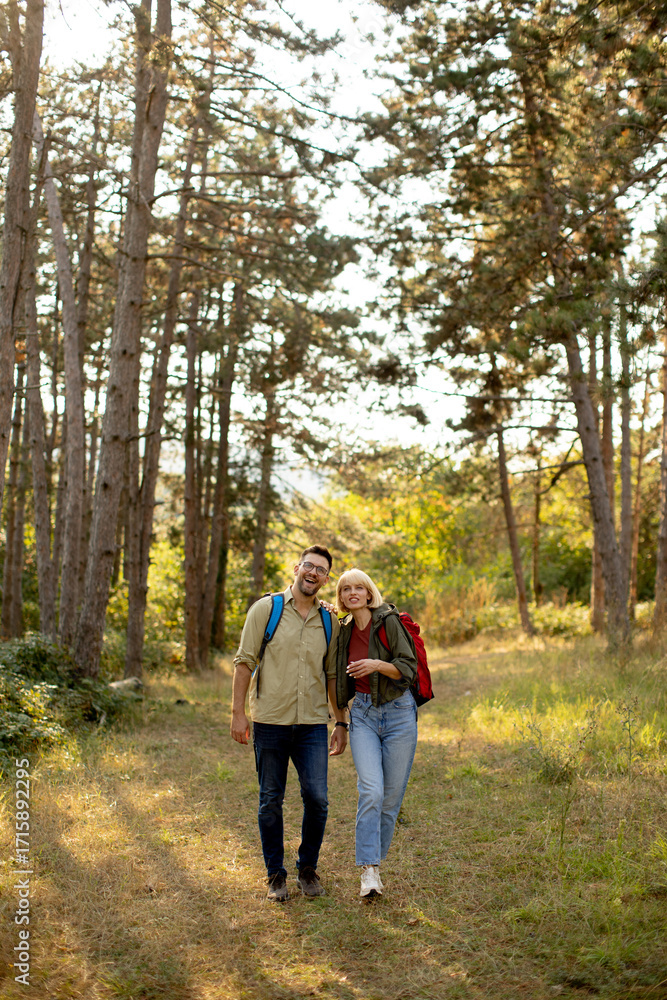 Fototapeta premium Couple enjoying a nature walk in a forest during the golden hour