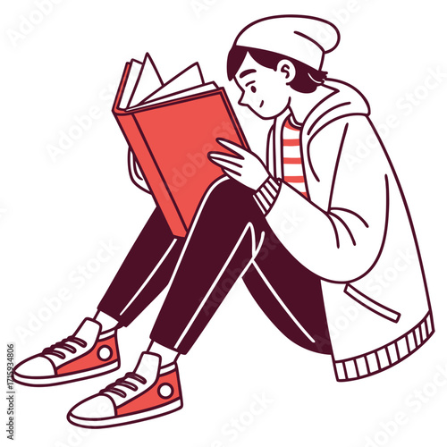 A young person wearing a beanie and hoodie sits cross legged reading a red book with a happy expression