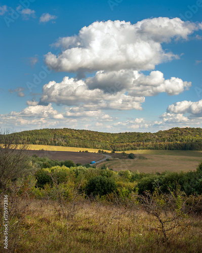 Hills of fields, arable land, forests at autumn colors under a blue sky with ...