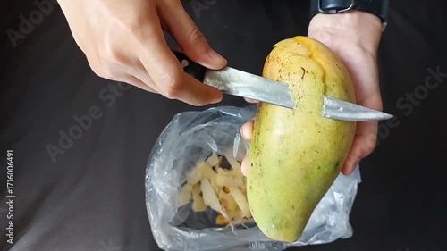 Hands Peeling Fresh Mango with Knife for Tropical Fruit Preparation