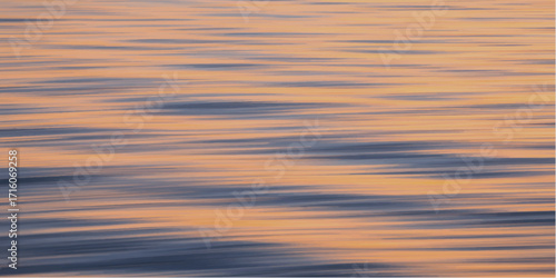 Vibrant orange and red clouds reflect over the calm sea as the sun dips below the horizon.