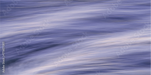 Blue sky with white clouds reflected on a ripple of blue water.