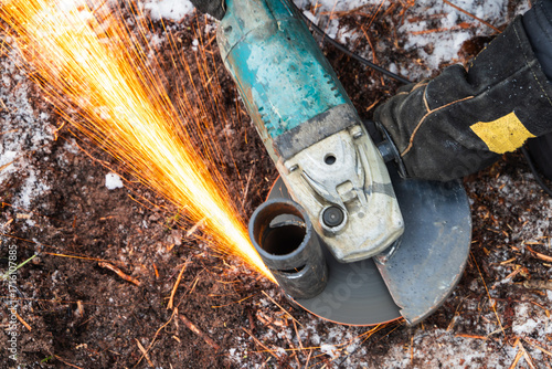 Wallpaper Mural Angle grinder sparks as a worker cuts metal pipe outdoors Torontodigital.ca