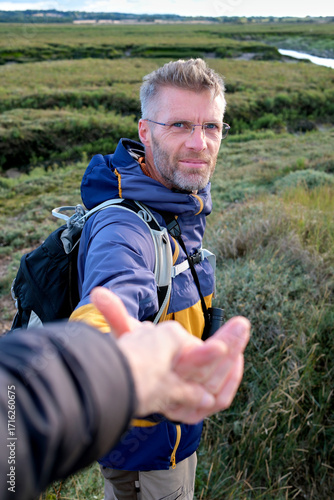 Helping Hand during Hike - Man Offering Supportive Outstretched Hand Through a Scenic Landscape