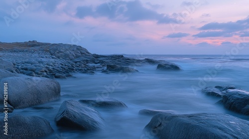 Serene coastal sunset with smooth ocean waves and dark rocks.