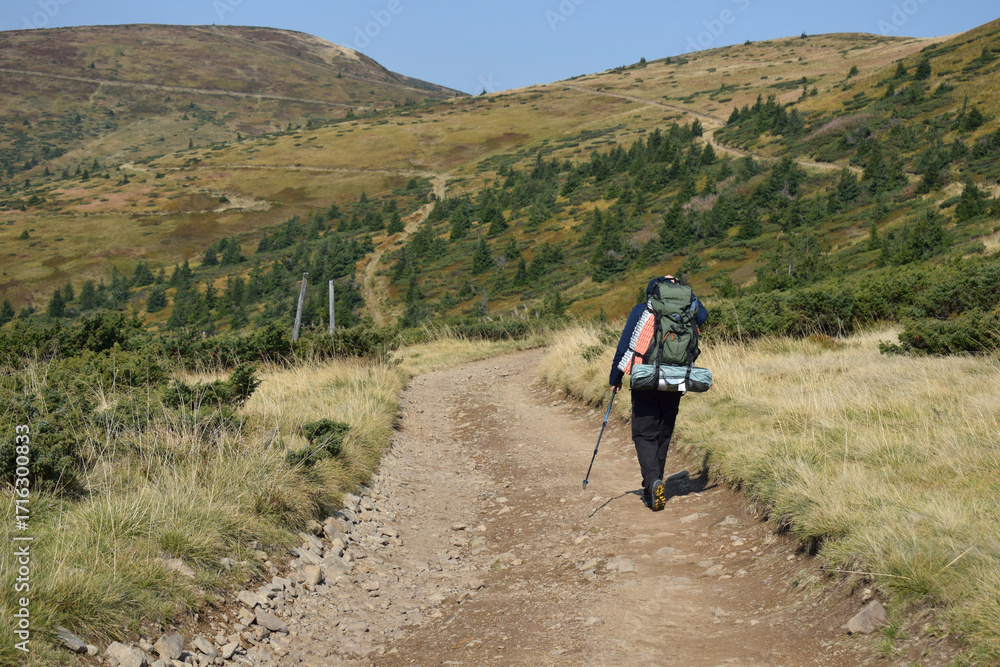 Obraz premium A man with a backpack is traveling in the mountains.