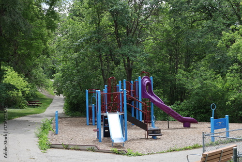 brightly coloured children's play structure at intersection of paved walking, running, cycling paths in summer