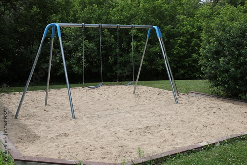 children's swing set in a sand box in summer
