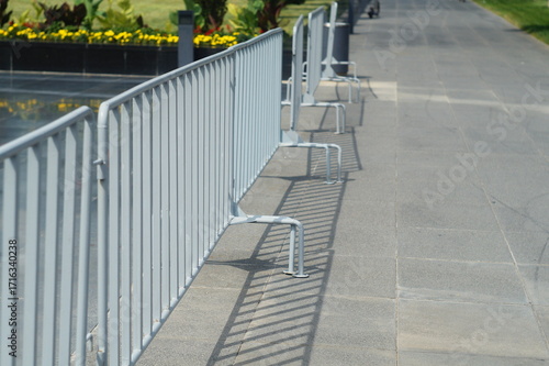 Light gray metal fences, barricades made of welded pipe with copy space on city street. Protruding legs for stability against overturning. Regulating movement of pedestrians, protesters, event guests