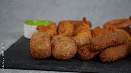 Assorted fried snacks with dipping sauces on a black slate serving platter ready