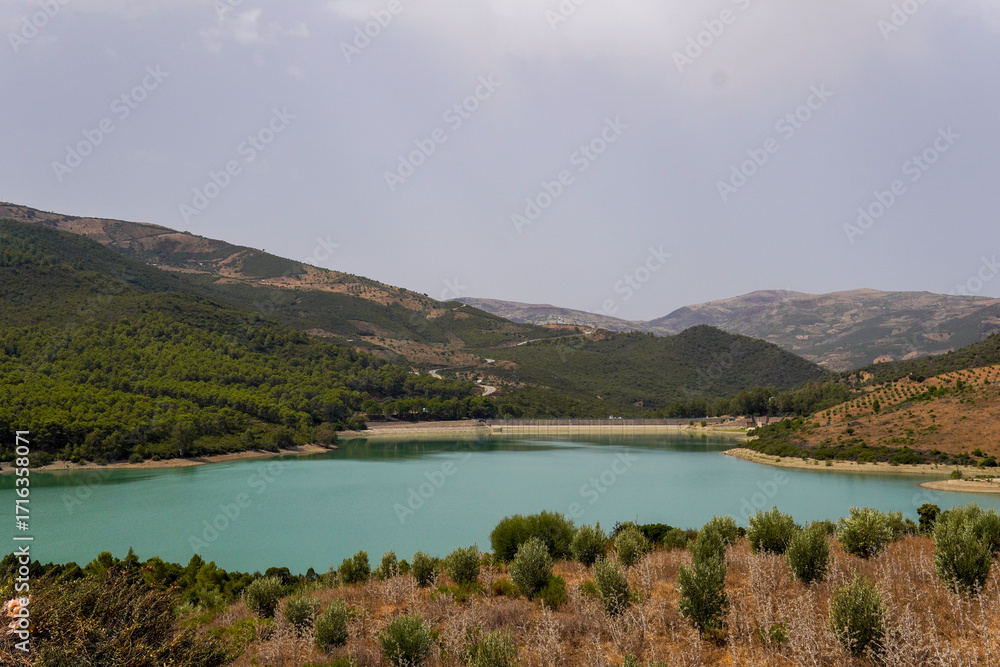 Fototapeta premium Scenic view of a turquoise lake surrounded by green mountains near Chefchaouen, Morocco. A peaceful nature and travel destination