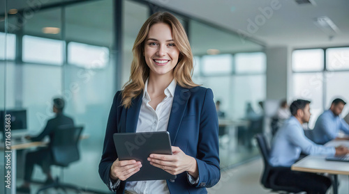 Businesswoman holding and using digital tablet in hand and looking with smile face in professional corporate company leader portrait in modern tech office workplace blur background