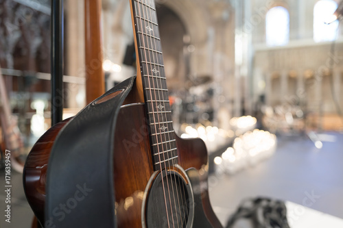 Shallow focus of the neck of a high quality, classical guitar on its stand. Located on stage, within a venue at a cathedral in England.