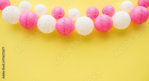 Pink and white paper lanterns garland Festive party decoration Flat lay style Yellow background