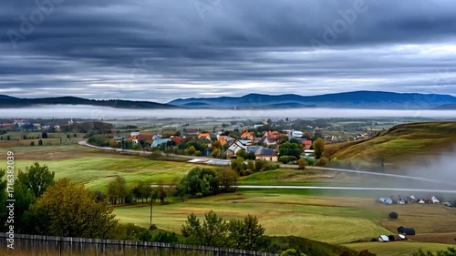 Serene Landscape with Misty Mountains and Village Under Overcast Sky