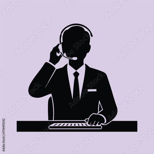 Silhouette of a professional man in a suit wearing a headset and working at a keyboard on a desk