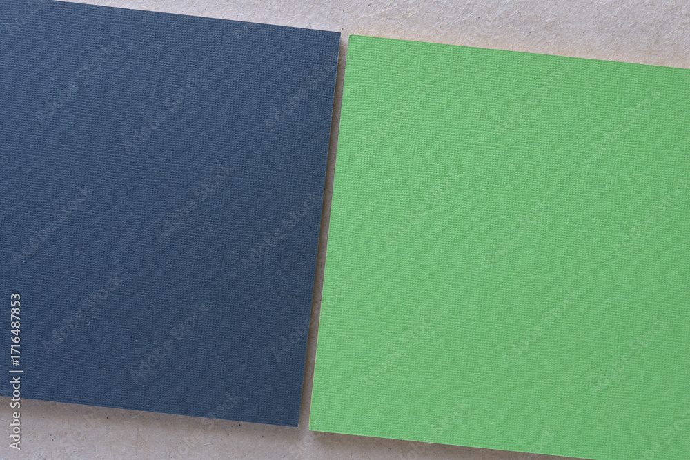 Fototapeta premium navy blue and green paper square pads on blank gray crafting paper