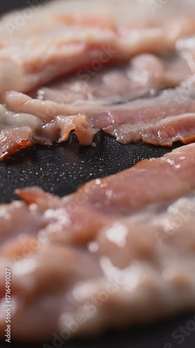 Time-lapse of bacon frying in a pan. It sizzles as it transforms from raw to a crispy, appetizing piece. Smoke rises and fat splatters during cooking.