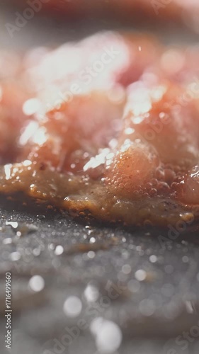Closeup slider shot of fresh bacon being flipped on a griddle. 4K cinematic footage.