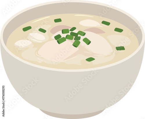 A close-up, overhead view of a bowl of creamy chicken and dumplings soup, garnished with chopped green onions.