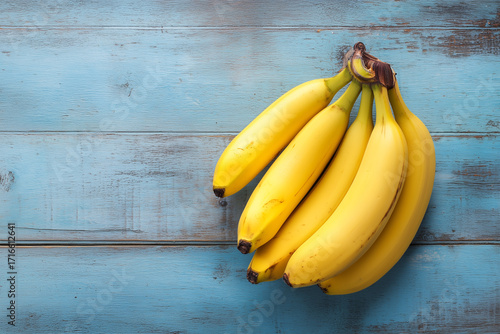 Fresh bunch of yellow bananas resting on a blue wooden surface
